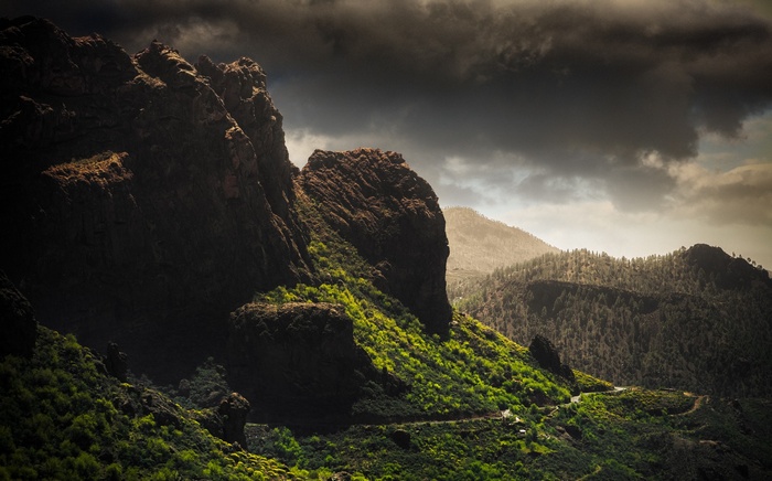 Dramatic mountain landscape with green slopes and dark clouds