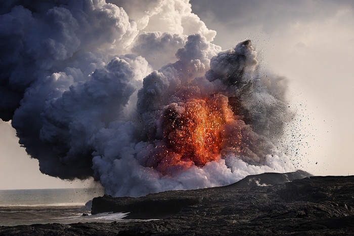 Volcanic eruption with lava and smoke over the sea