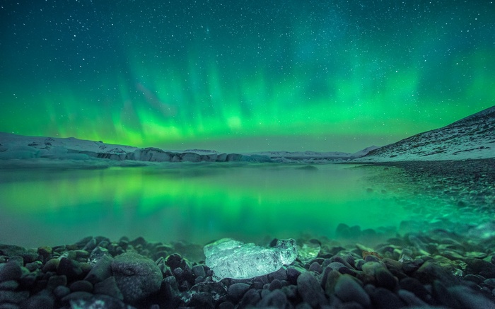 Aurora Borealis over a glacial lake with ice chunks