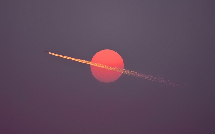 Airplane flying through the sun at sunset