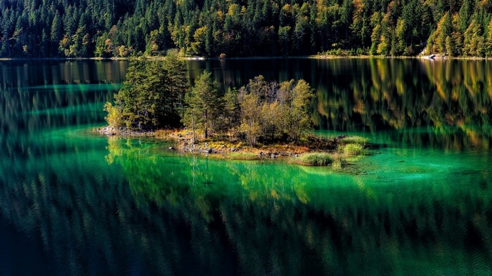 Island in a clear green lake surrounded by a forest