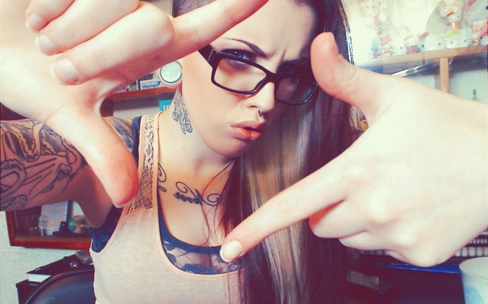 Woman with piercings and glasses framing her face