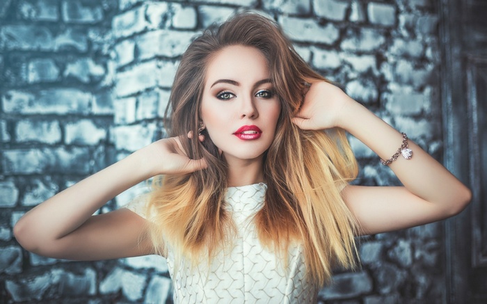 Woman with blonde hair in front of a brick wall