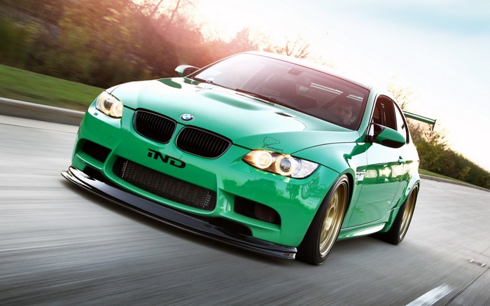 Green BMW M3 with racing decals on a road