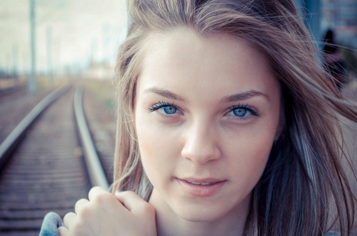 Young woman with blue eyes on train tracks