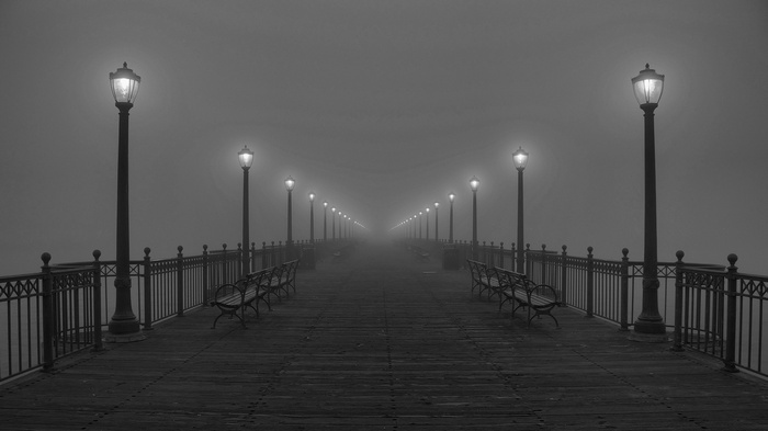 Pier with street lights and benches in fog