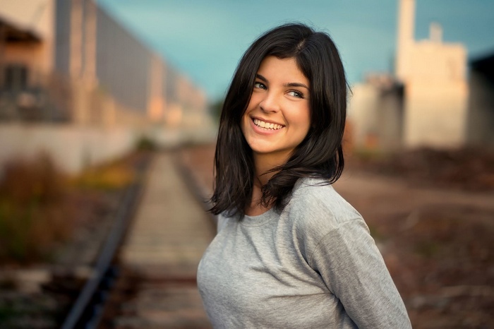 Young woman with dark hair smiling outdoors