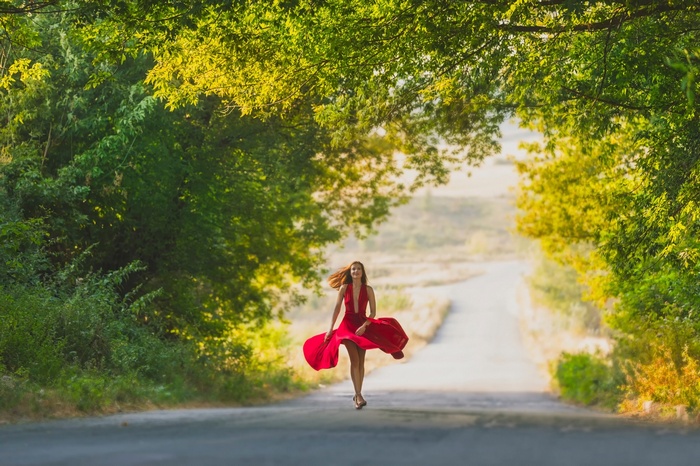 Woman in red dress running on a road