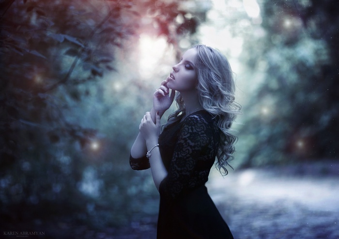 Woman with blonde hair in a dark dress in a forest