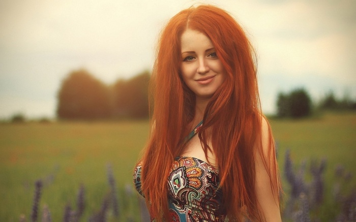 Redhead woman in a patterned dress in a field