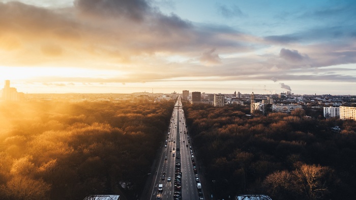 Berlin cityscape with a long road and forest at sunset
