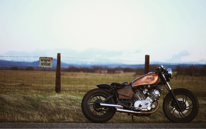 Bobber motorcycle parked by a fence