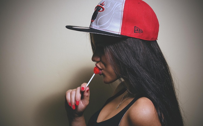 Woman in Miami Heat hat eating a lollipop