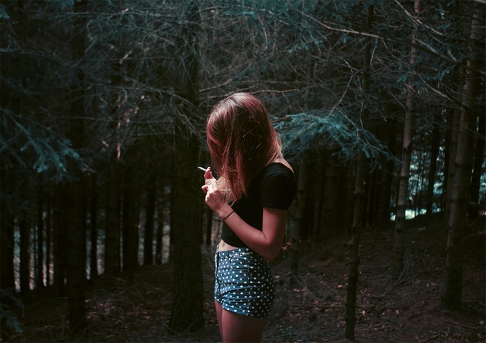 Woman smoking in a dark forest