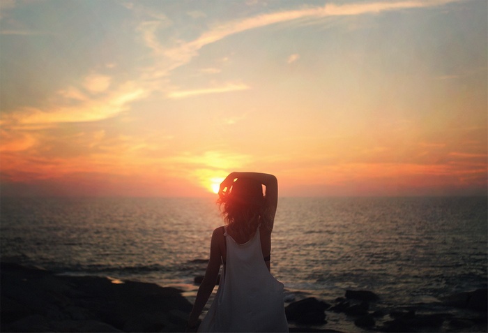 Woman watching sunset over the ocean