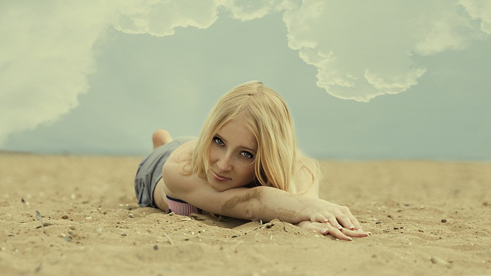 Woman with blonde hair lying on the sand