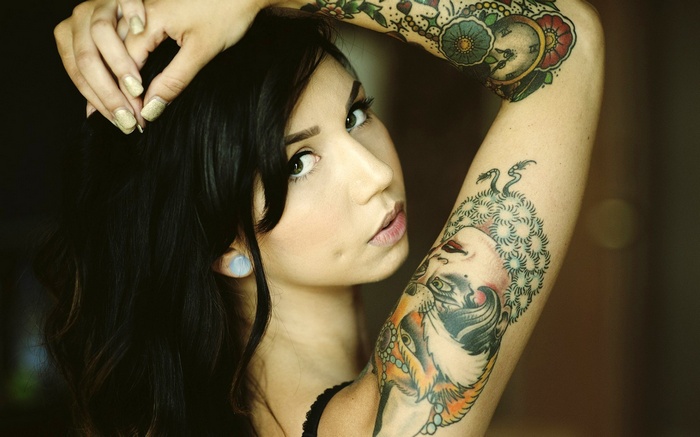 Woman with tattoos and hands on head