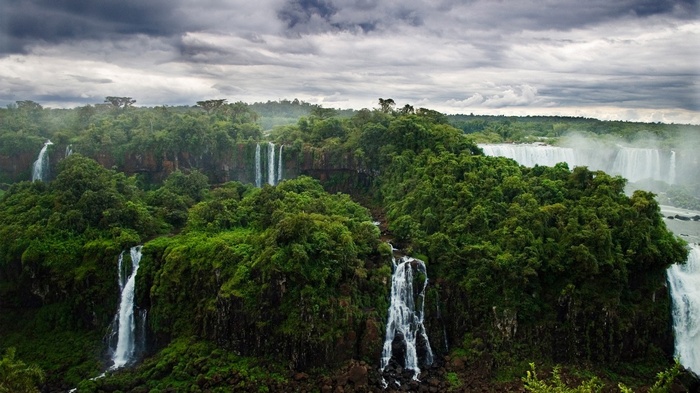 Tropical forest with multiple waterfalls under a cloudy sky