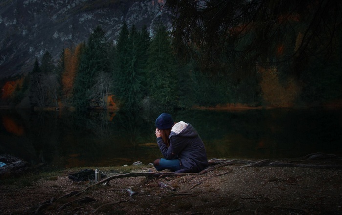 Woman sitting by a lake in the forest