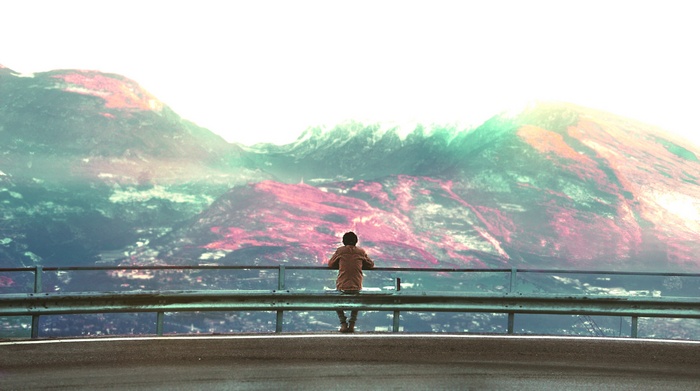 Person sitting on a railing overlooking mountains