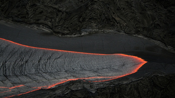 Molten lava flowing through dark volcanic rock formations