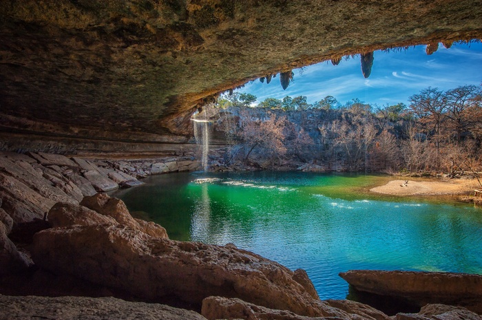 Waterfall cascading into a natural pool inside a cave