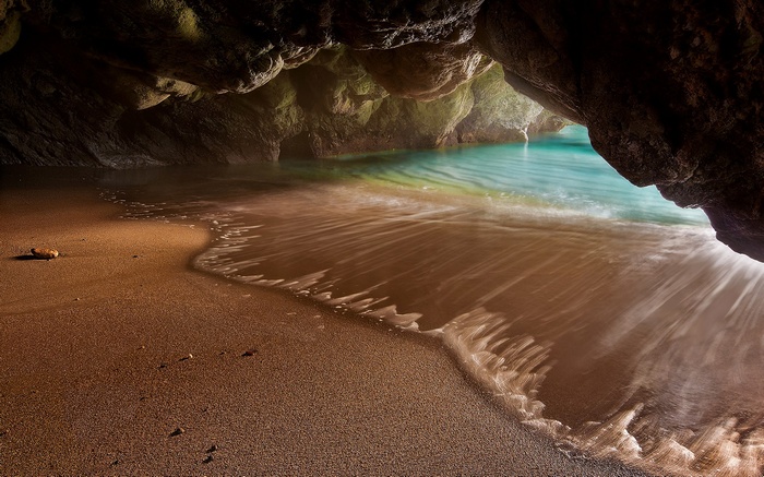 Hidden beach cave with turquoise water and sand