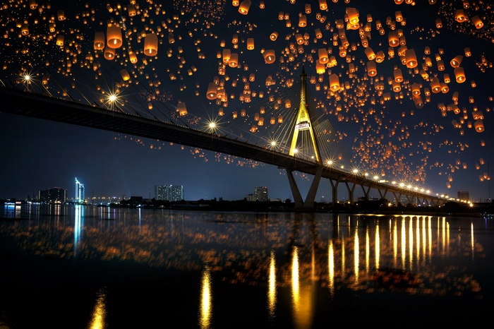 Night sky lanterns over a bridge and river
