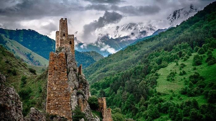 Ancient stone towers on a rocky outcrop in a mountain valley