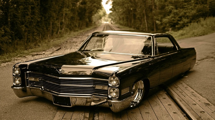 Black Cadillac lowrider on railroad tracks