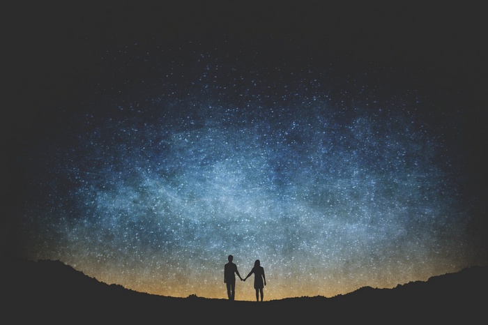 Couple holding hands under a starry sky