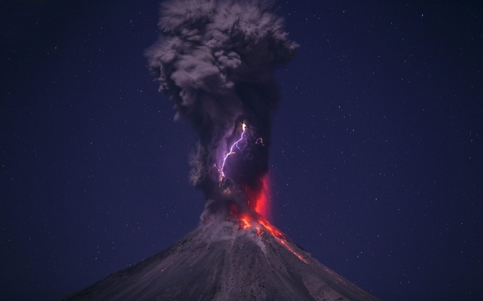 Volcano erupting with lightning at night
