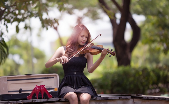 Asian woman playing violin in a park