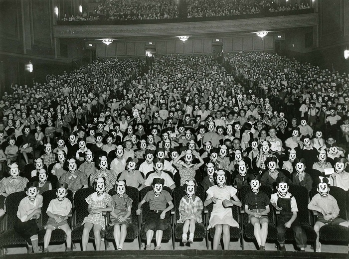 Audience wearing Mickey Mouse masks in a theater