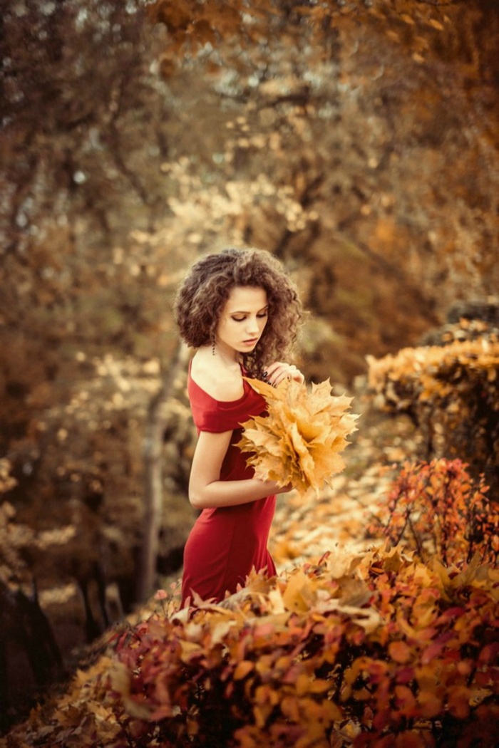 Ksenia Malinina in a red dress holding autumn leaves