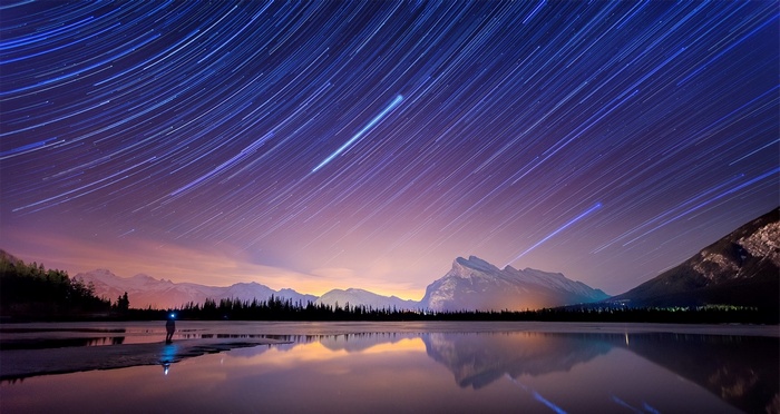 Star trails over Banff National Park lake with mountains