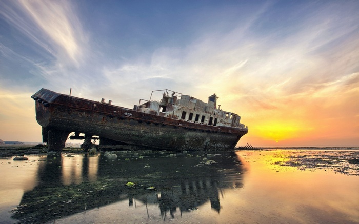 Shipwreck on the coast at sunset with reflection