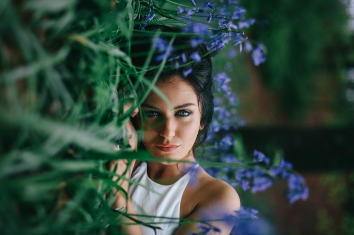 Aurela Skandaj surrounded by greenery and blue flowers