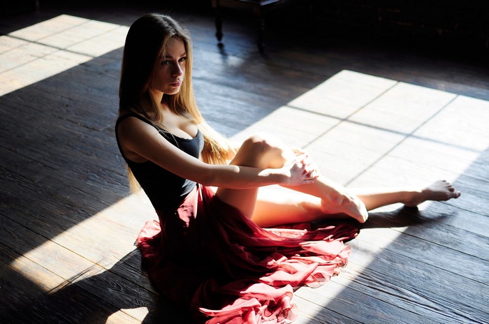 Ballerina in a red skirt sitting on the floor