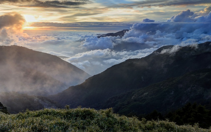 Sunset over mountains with clouds and grass