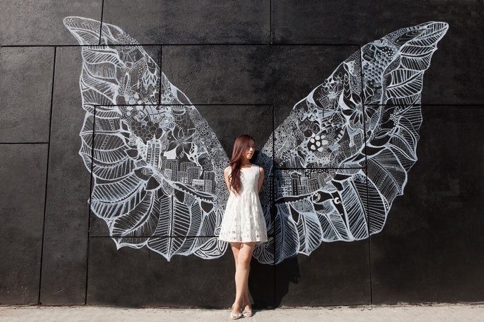 Woman in white dress with angel wings mural