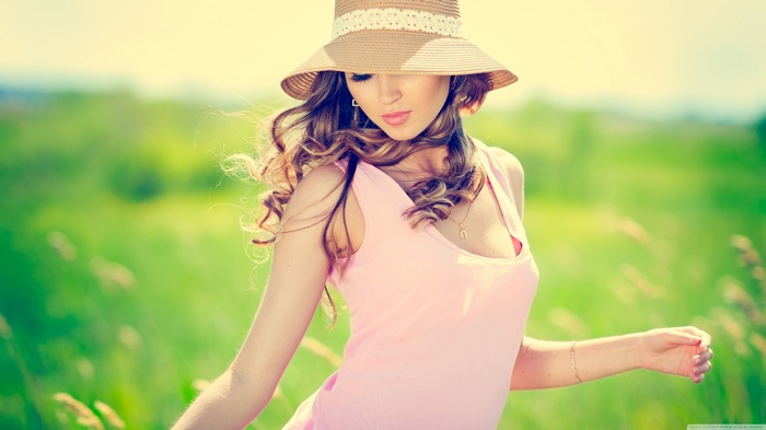 Woman in a pink dress and straw hat in a field