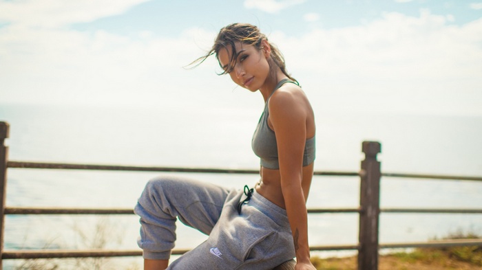 Woman in Nike sports bra and sweatpants sitting outdoors
