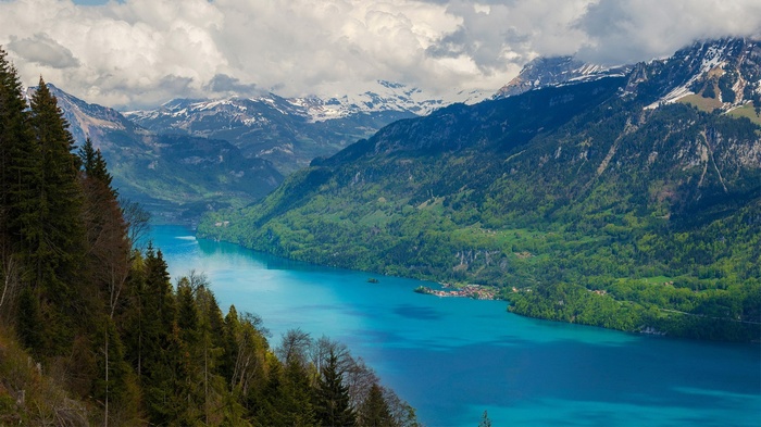 Turquoise lake surrounded by green mountains and snow-capped peaks