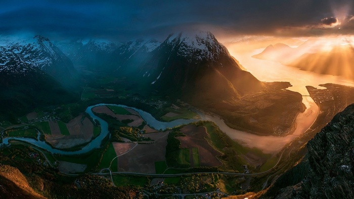 Panoramic view of mountains, river, and town in Norway at sunset