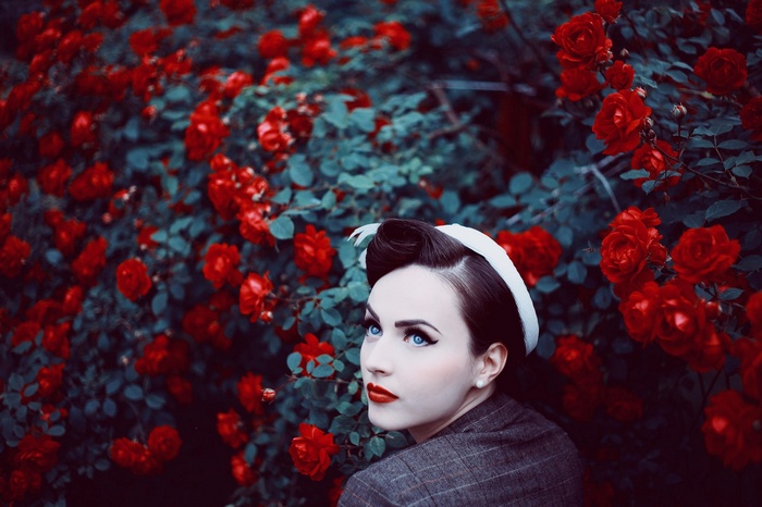 Woman with blue eyes and red lipstick in roses
