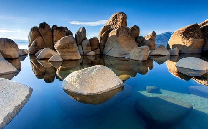 Rocks in a calm lake under a blue sky