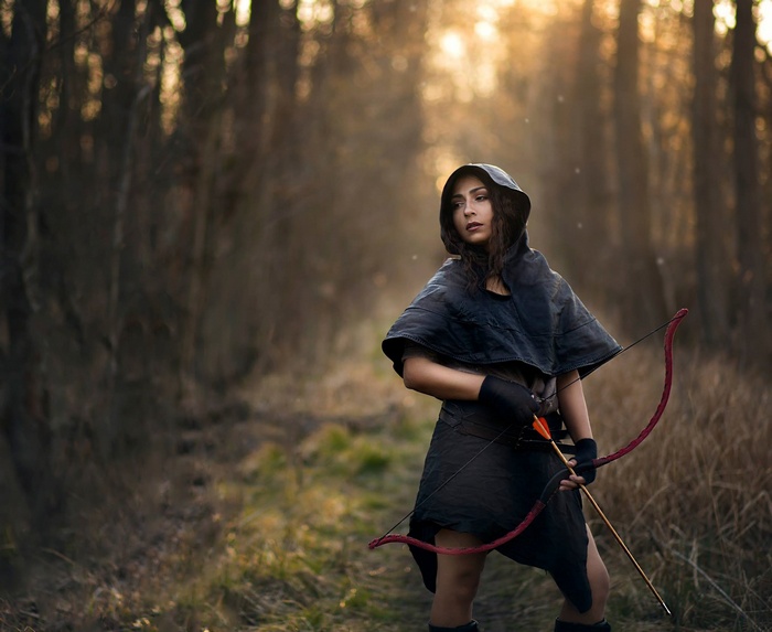 Woman with bow and arrow in forest