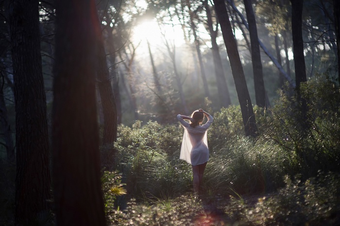 Woman in a white dress in a sunlit forest