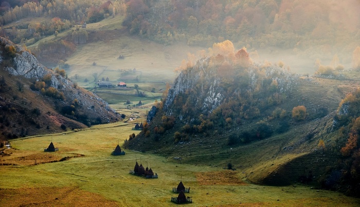 Misty valley with haystacks in Romania